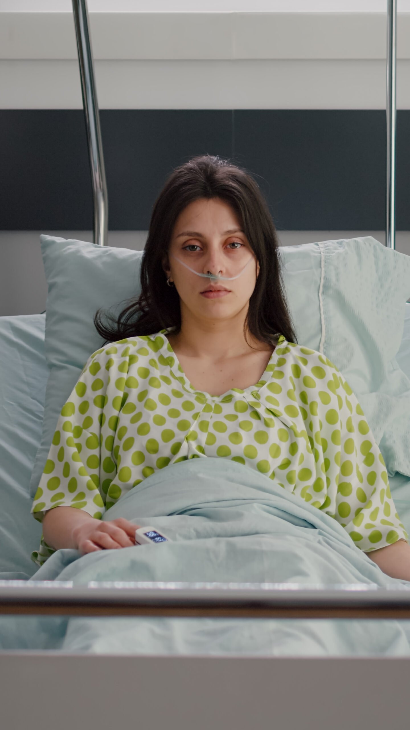 Sick woman with nasal oxygen tube looking into camera resting in bed recovering after respiratory surgery. Patient with breathing disorder waiting for illness treatment in hospital ward